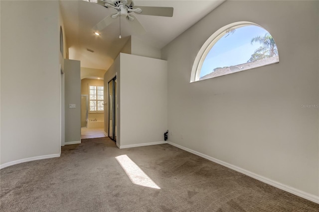 carpeted spare room featuring vaulted ceiling and ceiling fan