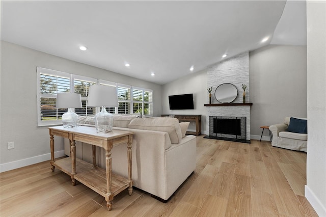 living room featuring a fireplace, vaulted ceiling, and light hardwood / wood-style floors