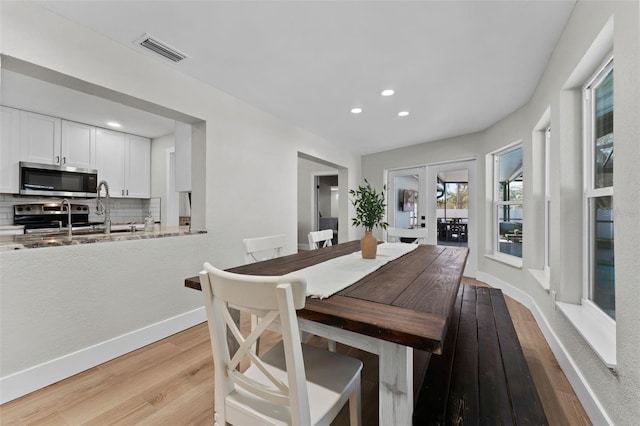 dining space with light wood-type flooring, french doors, and sink