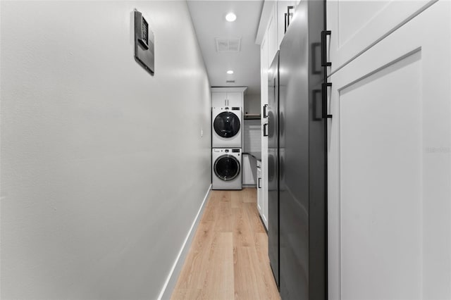 hallway with light hardwood / wood-style flooring and stacked washer / drying machine