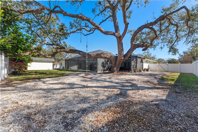 rear view of property featuring glass enclosure and a lawn