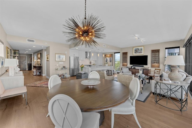 dining area with light wood-type flooring and a chandelier