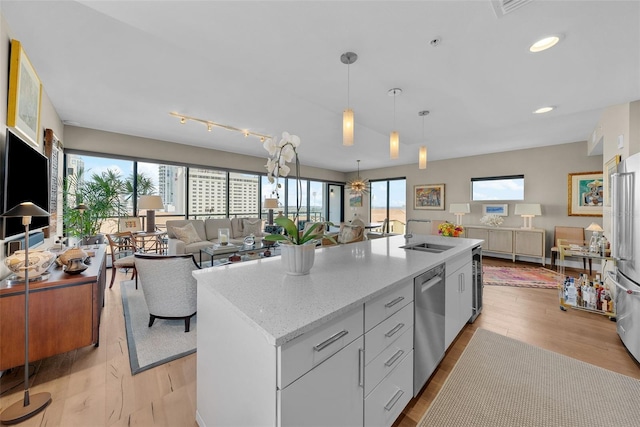 kitchen featuring an island with sink, appliances with stainless steel finishes, white cabinets, and light wood-type flooring