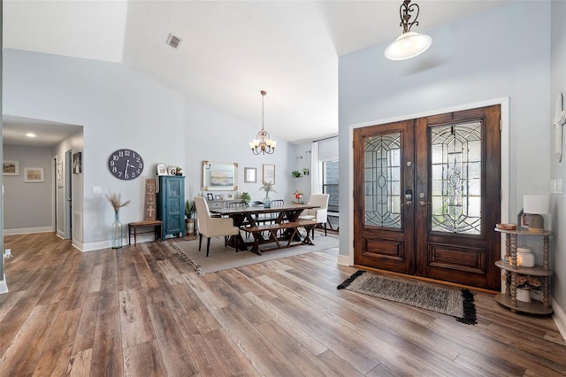 foyer entrance with french doors, high vaulted ceiling, a chandelier, and hardwood / wood-style floors