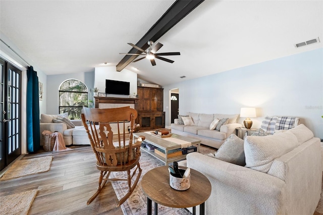 living room with ceiling fan, lofted ceiling with beams, and light wood-type flooring