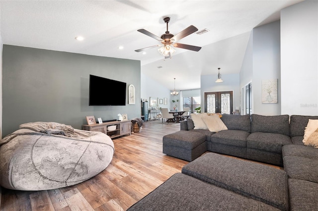 living room featuring ceiling fan with notable chandelier, high vaulted ceiling, light hardwood / wood-style floors, and french doors