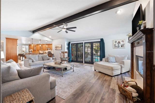 living room featuring vaulted ceiling with beams, wood-type flooring, a fireplace, and ceiling fan