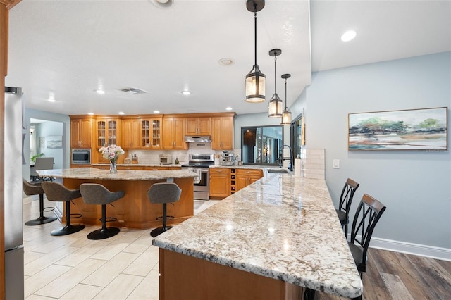 kitchen featuring a breakfast bar, sink, kitchen peninsula, stainless steel appliances, and backsplash