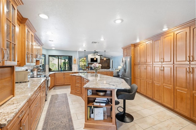 kitchen with light stone counters, stainless steel appliances, a center island, and a kitchen bar