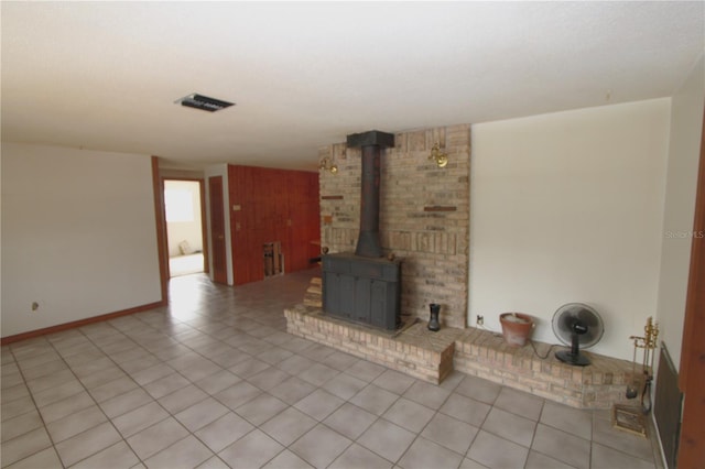 unfurnished living room featuring light tile patterned flooring and a wood stove