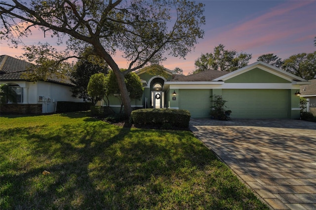 ranch-style home featuring a garage and a yard