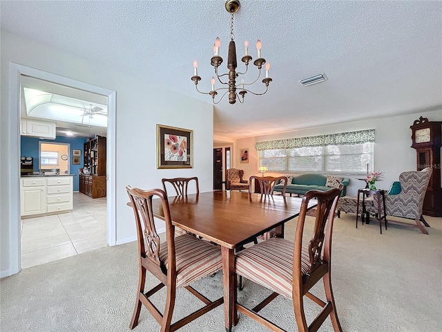 dining space featuring light colored carpet, an inviting chandelier, light tile patterned floors, visible vents, and a textured ceiling