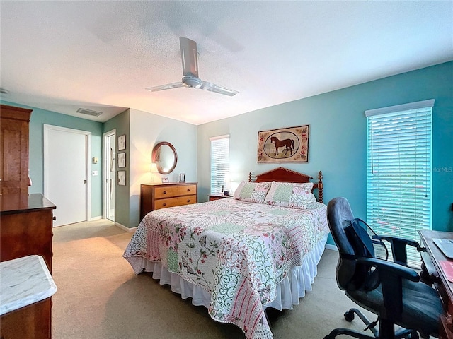 bedroom with ceiling fan, visible vents, baseboards, light carpet, and a textured ceiling