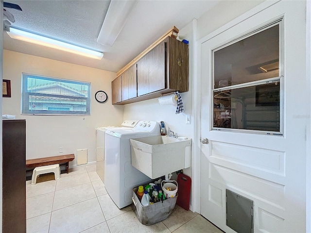 clothes washing area with a sink, cabinet space, washer and clothes dryer, and light tile patterned flooring