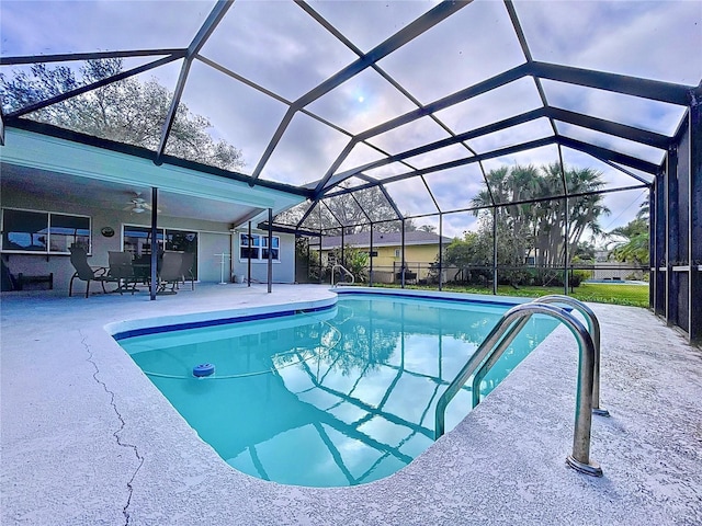 pool featuring a ceiling fan, glass enclosure, and a patio area