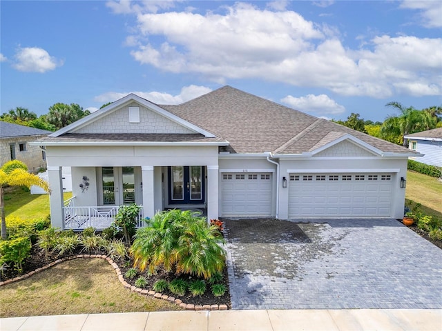 view of front of home with a garage, a shingled roof, covered porch, decorative driveway, and stucco siding