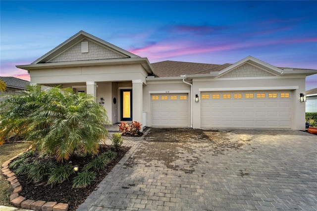 view of front facade with an attached garage, decorative driveway, and stucco siding