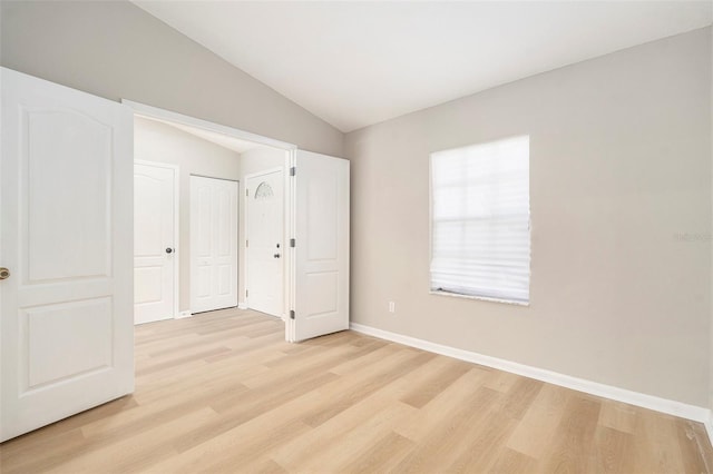 unfurnished bedroom featuring lofted ceiling and light hardwood / wood-style flooring