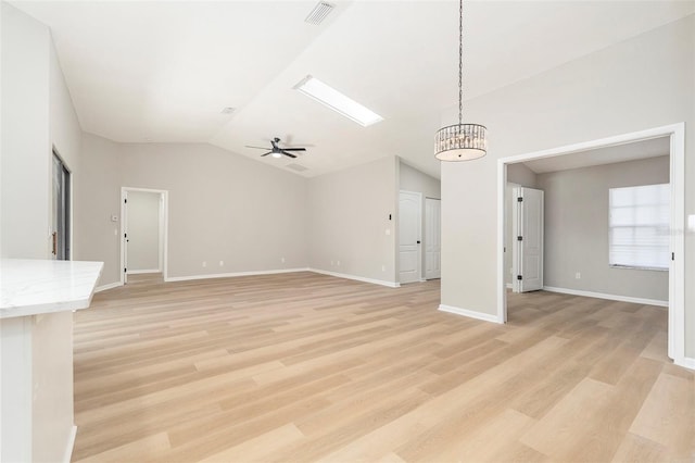 unfurnished living room featuring ceiling fan with notable chandelier, light hardwood / wood-style flooring, and lofted ceiling with skylight