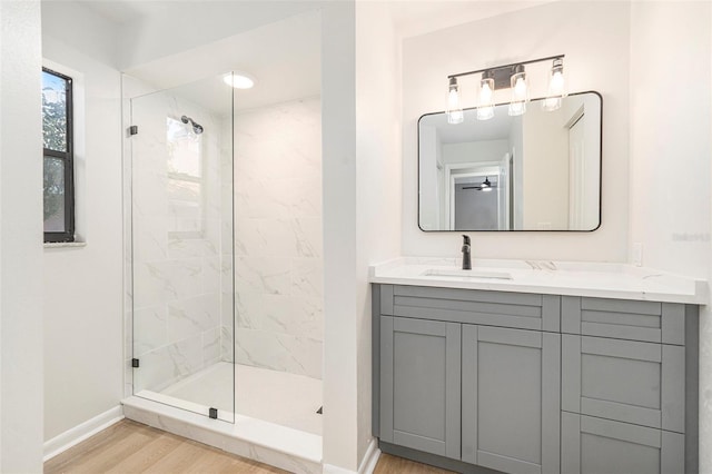 bathroom featuring vanity, tiled shower, and wood-type flooring