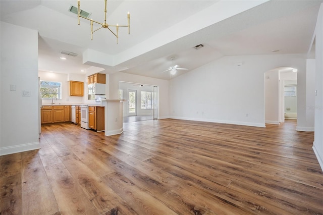 unfurnished living room featuring light wood-style flooring, visible vents, vaulted ceiling, and arched walkways