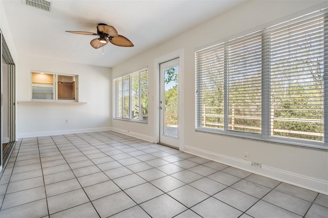 tiled spare room with visible vents, ceiling fan, and baseboards