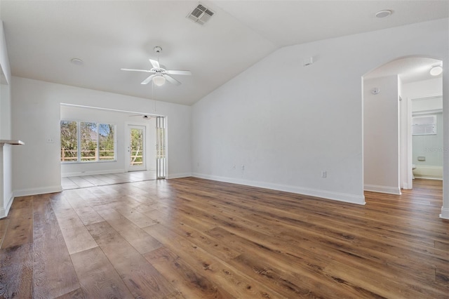 unfurnished living room with baseboards, arched walkways, a ceiling fan, lofted ceiling, and hardwood / wood-style floors