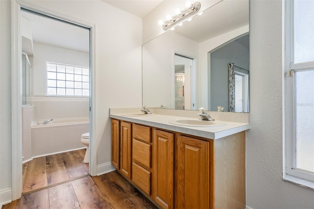 full bathroom with double vanity, a sink, a bath, and wood finished floors