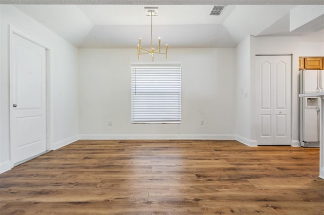 unfurnished dining area with baseboards, visible vents, lofted ceiling, wood finished floors, and an inviting chandelier