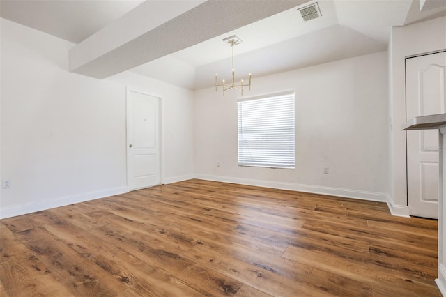 unfurnished dining area featuring lofted ceiling, a notable chandelier, wood finished floors, visible vents, and baseboards