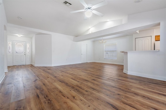 unfurnished living room featuring lofted ceiling, ceiling fan with notable chandelier, visible vents, baseboards, and wood-type flooring