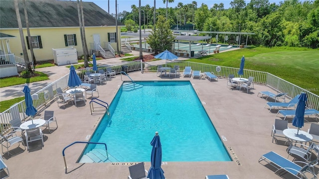 community pool featuring a patio, a lawn, and fence