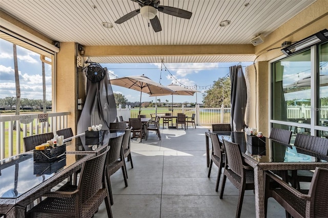 view of patio with outdoor dining area, fence, and a ceiling fan