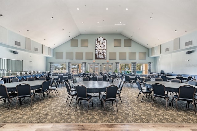 dining area with high vaulted ceiling, visible vents, and wood finished floors