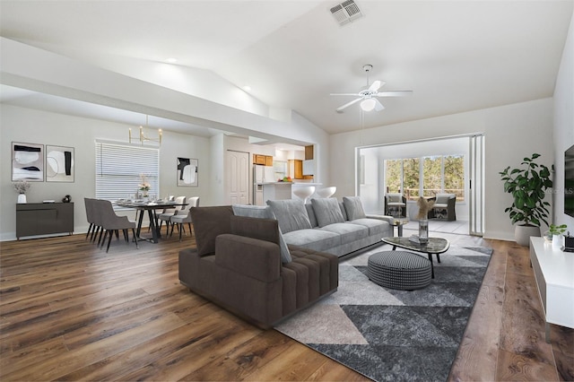 living room with lofted ceiling, visible vents, wood finished floors, baseboards, and ceiling fan with notable chandelier