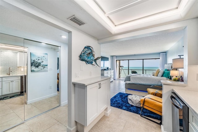 tiled bedroom with sink, a textured ceiling, and a water view