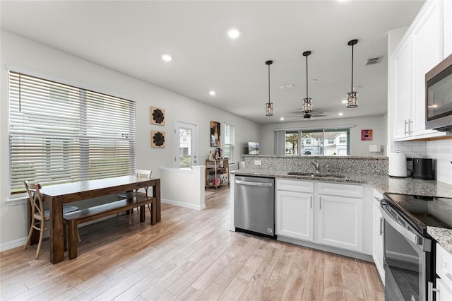 kitchen featuring pendant lighting, stainless steel appliances, visible vents, white cabinetry, and a sink