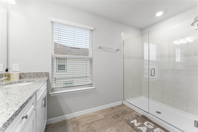 bathroom featuring wood finish floors, a shower stall, vanity, and baseboards