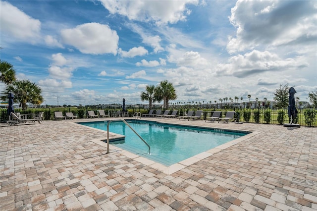 community pool with a patio and fence