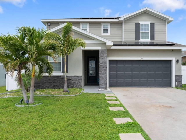 view of front of property featuring an attached garage, stone siding, solar panels, and a front yard