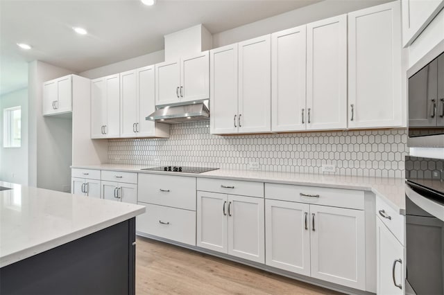 11885 Richmond Trl, Parrish, FL 34219 - kitchen with under cabinet range hood, wall oven, black electric cooktop, tasteful backsplash, and light wood finished floors