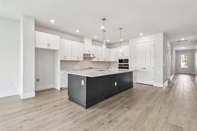 11885 Richmond Trl, Parrish, FL 34219 - kitchen with oven, under cabinet range hood, built in microwave, white cabinets, and baseboards