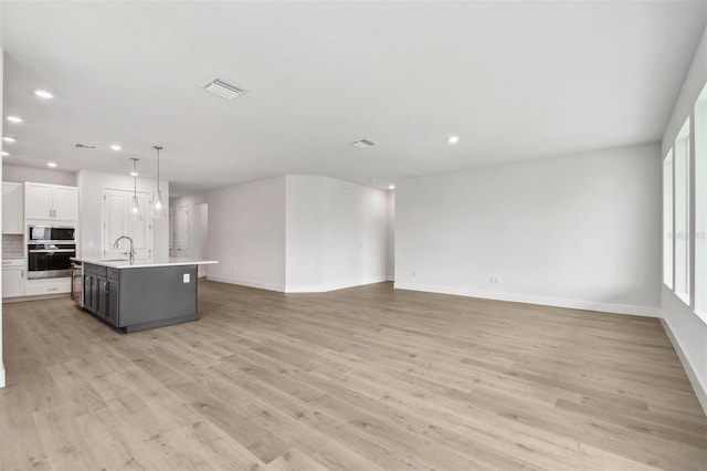 11885 Richmond Trl, Parrish, FL 34219 - unfurnished living room with recessed lighting, baseboards, a sink, and light wood-style flooring