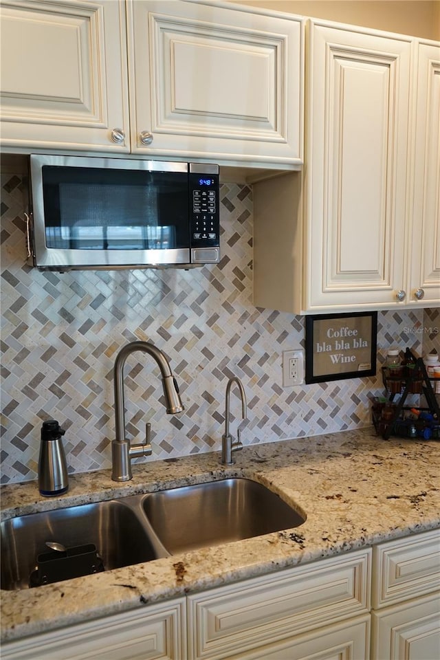 kitchen featuring light stone counters, sink, and backsplash