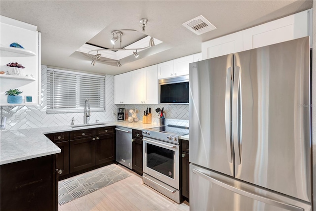 kitchen with a sink, visible vents, appliances with stainless steel finishes, open shelves, and a tray ceiling