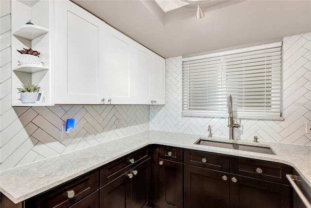 kitchen with a sink, white cabinetry, dishwasher, open shelves, and tasteful backsplash