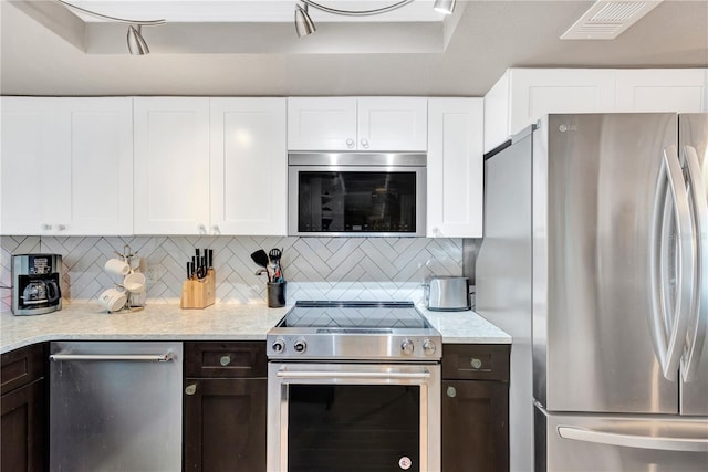 kitchen featuring stainless steel appliances, tasteful backsplash, white cabinetry, and dark brown cabinetry