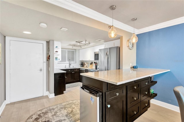 kitchen featuring decorative light fixtures, stainless steel appliances, crown molding, dark brown cabinets, and a sink