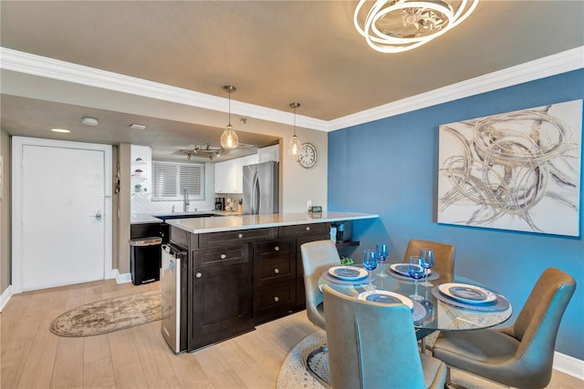 dining space featuring light wood finished floors, baseboards, and ornamental molding