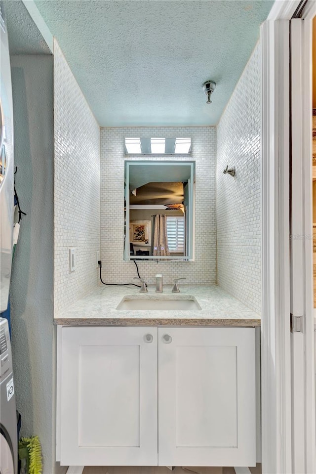 bathroom featuring a textured ceiling, vanity, and decorative backsplash